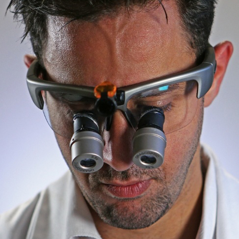 Close up of Doctor Ali wearing dental binoculars while treating a patient