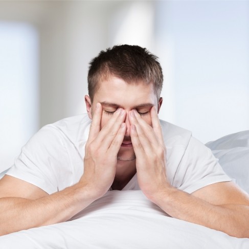 Man laying in bed and rubbing his eyes
